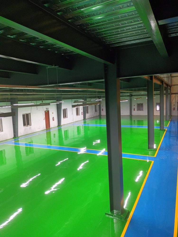 Lantai epoxy hijau dengan marka biru dan kuning pada gudang industri